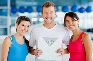 Three pals at a gym with a scale participating in the BetterTogether weight loss challenge.